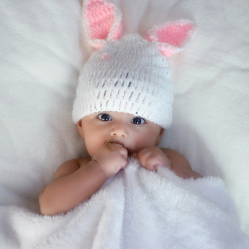 Bébé dans son lit avec une couverture et son bonnet avec des oreilles de lapin